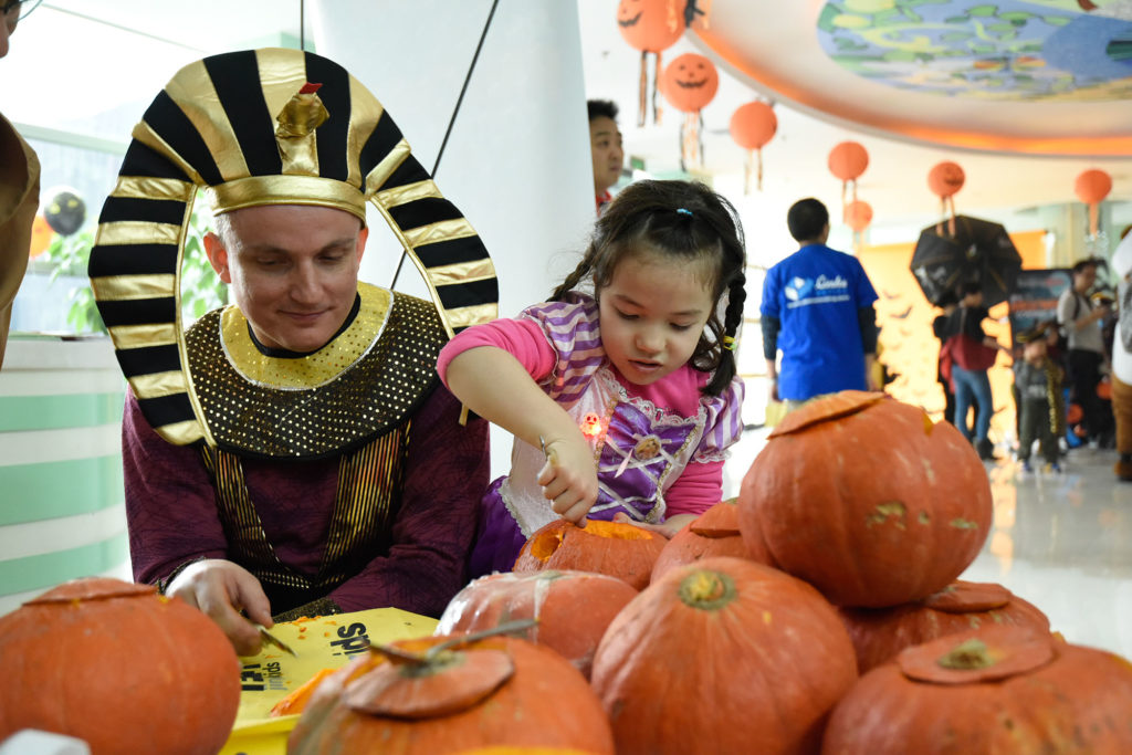 A pharaoh looks on as the princess carves her pumpkin
