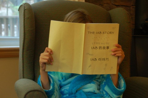 A child reading a physical copy of "The IAB Story"