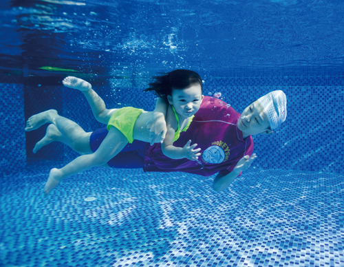 Coach Connie Sun guides Jingxin Ren (almost 3) in an underwater exercise