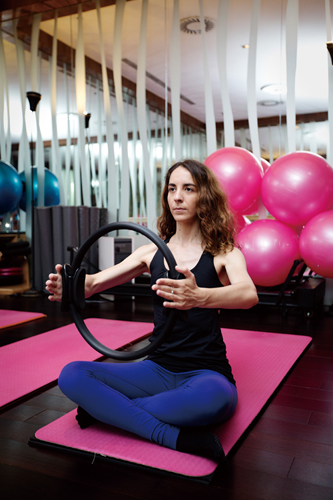 Instructor Eleonora Angelopoulos demonstrates a Pilates exercise with the magic circle
