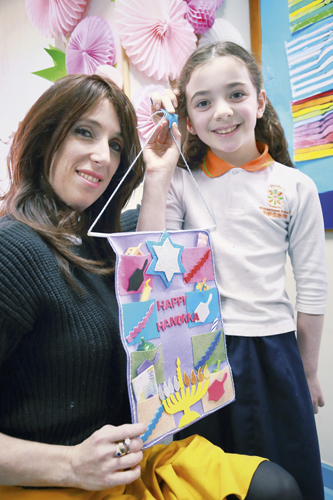 Ganeinu Teacher Chani Raskin and student Grunia Freundlich (age 8) display their finished hanging