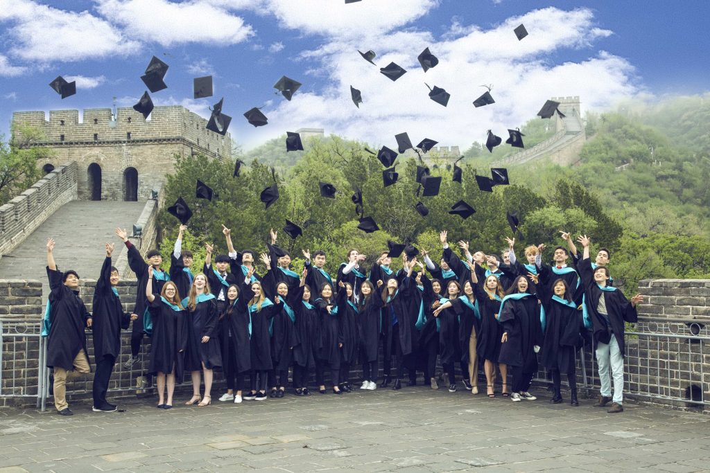 students throw their caps into the air at the great wall of china